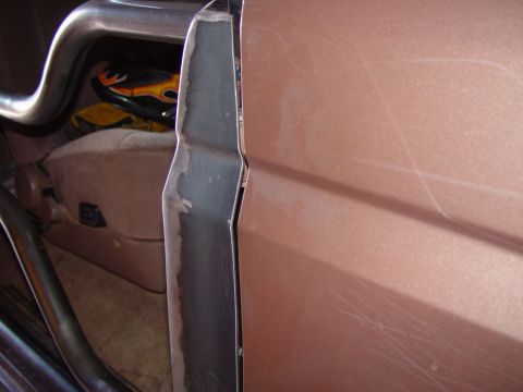 1993 Ford Bronco - Tight shot of a bare-steel latch/striker plate welded and bolted to the rear door jamb of a copper-brown Ford Bronco, with grinder-polished…