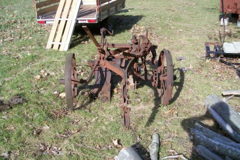 2000 Chevrolet Tahoe - Old farm equipment, likely a plow or cultivator, is heavily rusted and sits outdoors.