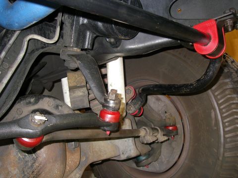 1990 Ford Bronco - Close-up view of a vehicle's suspension system, showing various metal components and red bushings.