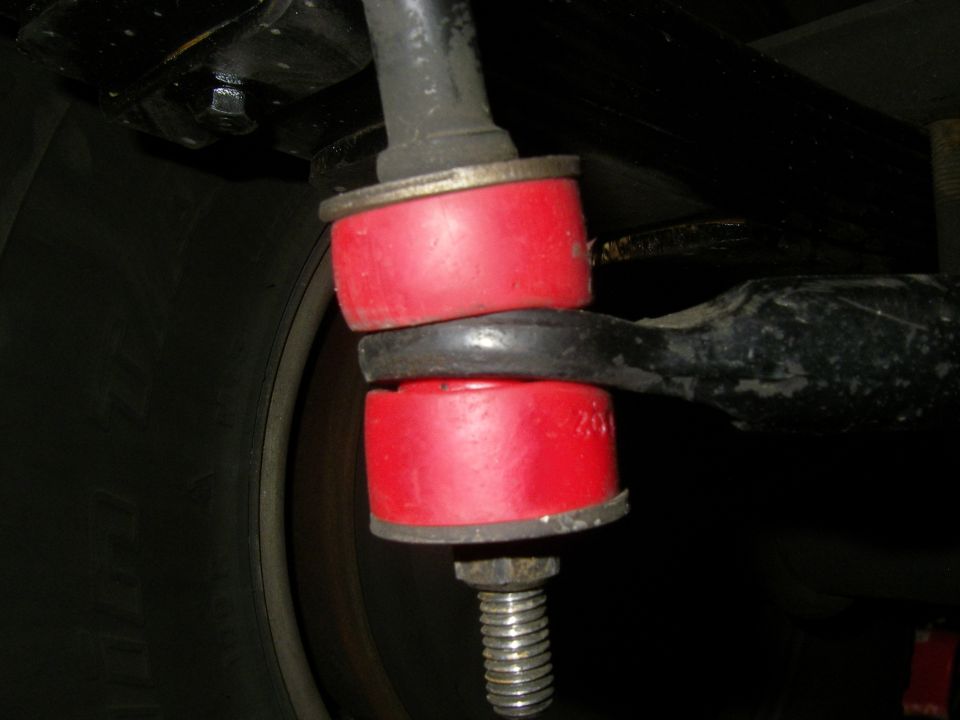 Sway bar end link with red polyurethane bushings and washers under a vehicle