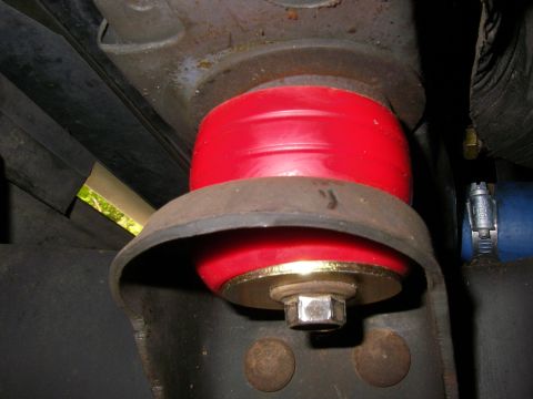 1990 Ford Bronco - Close-up view of a red suspension bushing mounted with a bolt and washer.