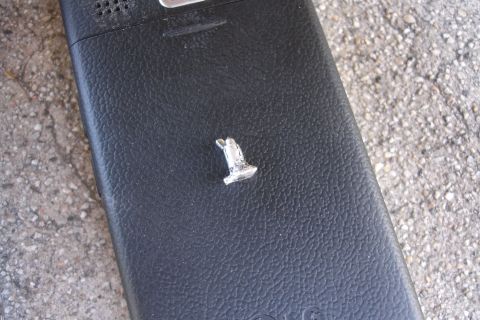 1992 Ford Taurus - A small metal object rests on a black, textured surface, with a concrete background.