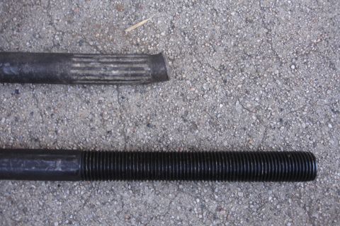 1992 Ford Taurus - Comparison of two metal rods, one splined and one threaded, on a concrete background.