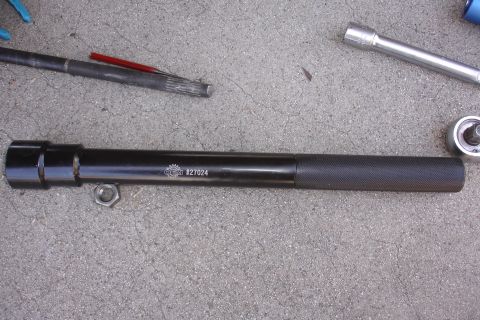 1992 Ford Taurus - A close-up view of a specialized automotive tool and a nut lying on a concrete surface.