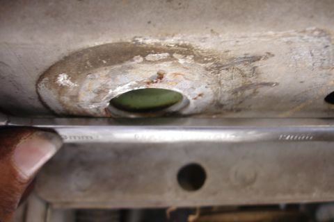 1992 Ford Taurus - A wrench is positioned near a corroded section of a vehicle's subframe, showing a circular opening.