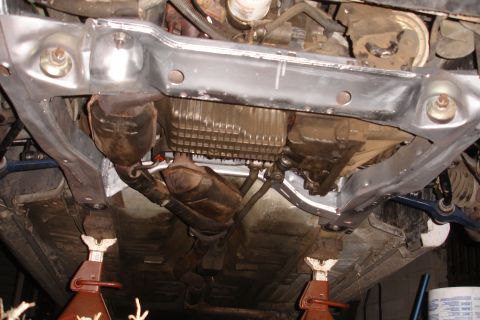 1992 Ford Taurus - Underside view of a car's subframe and exhaust system, with components on jack stands.