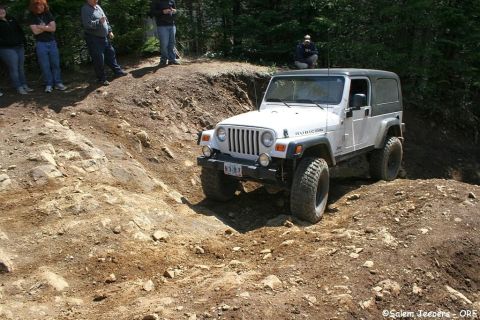 2005 Jeep Wrangler - A white 2005 Jeep Wrangler Rubicon navigates a challenging dirt trail with onlookers present.