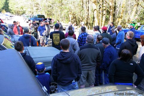 2005 Jeep Wrangler - A group of people stand around a 2005 Jeep Wrangler and other vehicles in a wooded area.