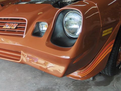 1980 Chevrolet Camaro - Close-up of the front end of a 1980 Chevrolet Camaro Z28, showing the grille, headlights, and distinctive racing stripes on the fender.