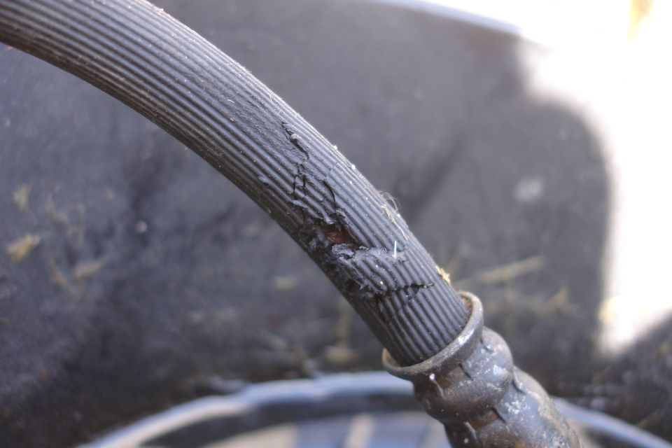 Cracked black ribbed rubber hose with metal fitting