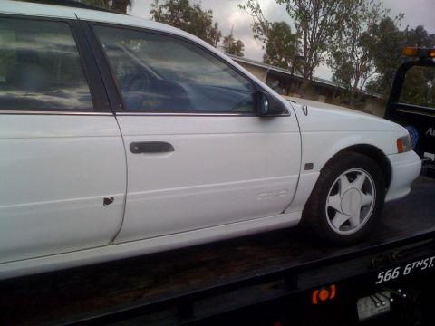 1992 Ford Taurus - White 1992 Ford Taurus station wagon loaded onto a tow truck.
