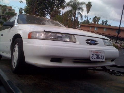 1992 Ford Taurus - The front end of a white Ford Taurus is visible, secured to a trailer.