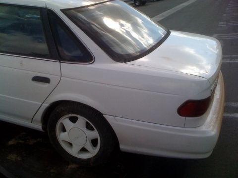 1992 Ford Taurus - Rear view of a white 1992 Ford Taurus sedan, showing the quarter panel and taillight.