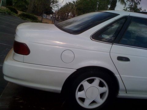 1992 Ford Taurus - Rear view of a white 1992 Ford Taurus, showing the quarter panel and wheel.