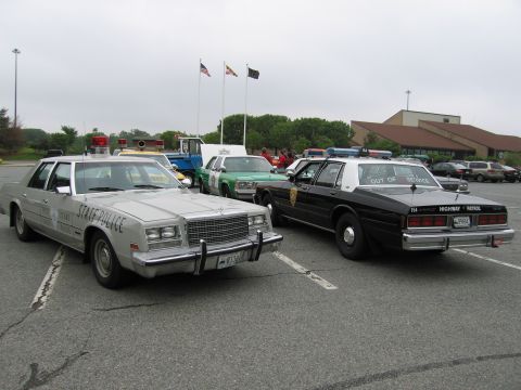 1991 Ford Crown Victoria - Multiple police vehicles are parked in an outdoor lot under a cloudy sky.