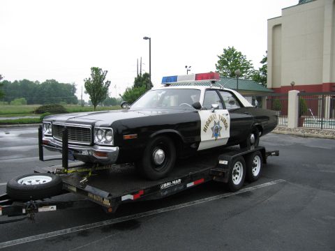 1991 Ford Crown Victoria - This police car, likely a 1975 Dodge Monaco, is being transported on a trailer.