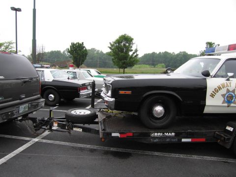 1991 Ford Crown Victoria - A police car is being transported on a trailer, with other vehicles visible in the background.