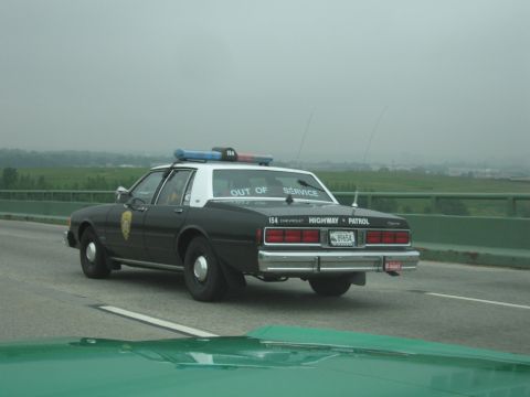 1991 Ford Crown Victoria - This Chevrolet Caprice Highway Patrol car, marked "OUT OF SERVICE", is seen from the rear with its light bar illuminated.