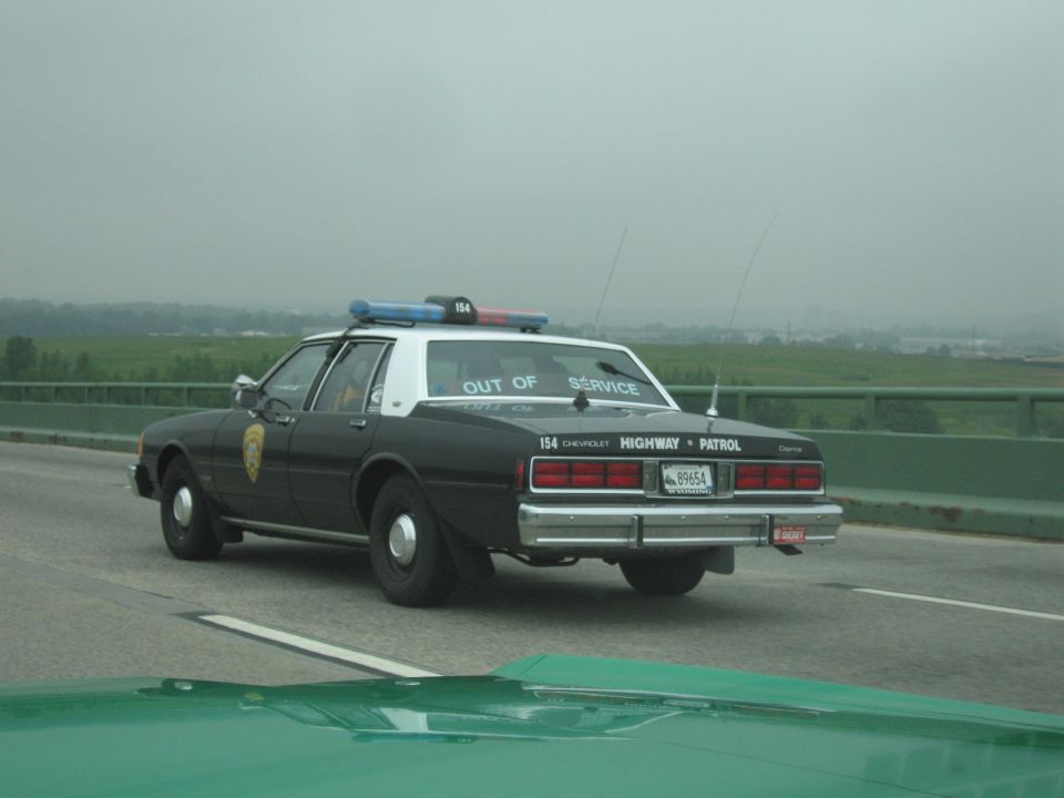 Black-and-white Chevrolet Highway Patrol sedan out of service on highway