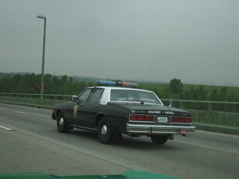 1991 Ford Crown Victoria - Chevrolet Caprice police car marked 'HIGHWAY PATROL' is seen on the road.