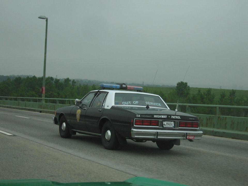 Black-and-white Chevrolet Highway Patrol cruiser 154 on a highway bridge
