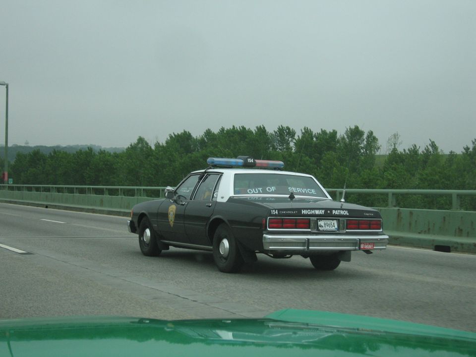 Black-and-white Highway Patrol cruiser 154 driving on a highway bridge