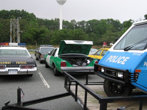 1991 Ford Crown Victoria - A green and white police car, identified as a 1991 Ford Crown Victoria, is parked with its trunk open, alongside other police vehicles.