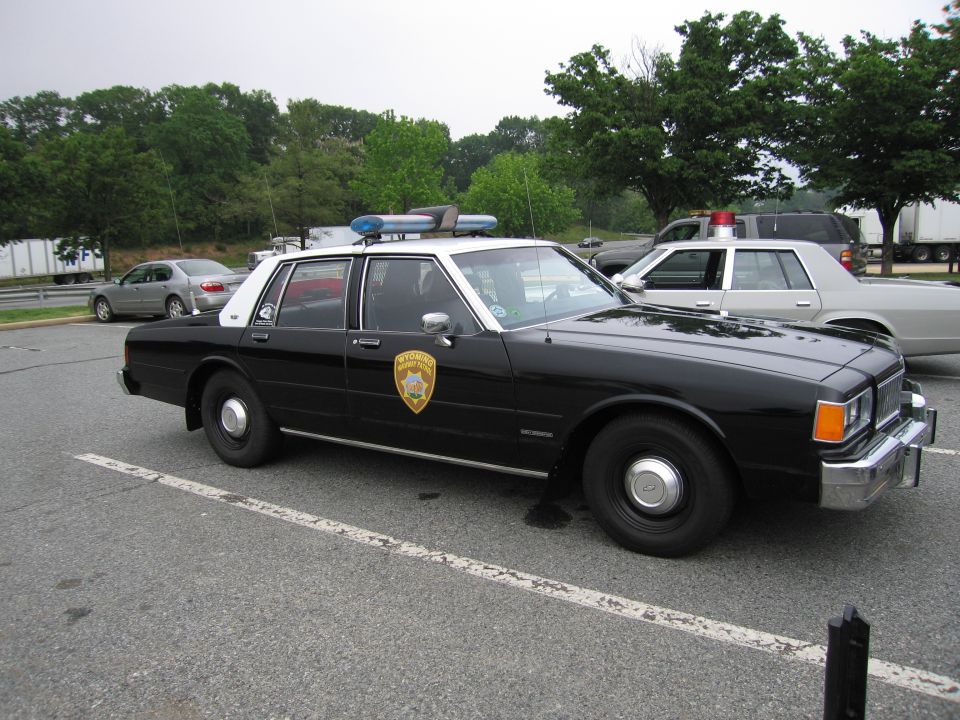 Black-and-white Chevrolet Caprice police sedan with rooftop lightbar parked in a lot