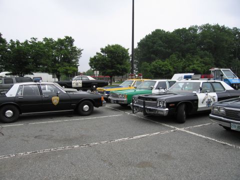 1991 Ford Crown Victoria - A collection of police vehicles, a black and white patrol car with "Highway Patrol" markings, are parked together in a lot.