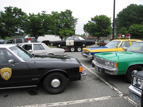 1991 Ford Crown Victoria - Multiple police vehicles, including a black Wyoming Highway Patrol car, are parked together in an outdoor lot.