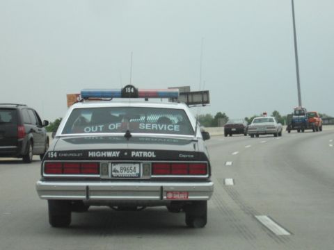 1991 Ford Crown Victoria - A Chevrolet Caprice police car, marked "OUT OF SERVICE", is seen on the highway with other vehicles.