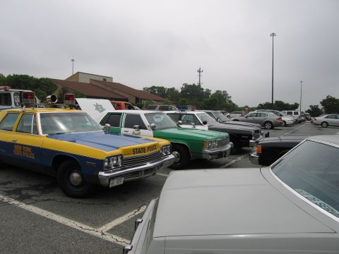 1991 Ford Crown Victoria - Several police cars are parked in a lot under a cloudy sky.