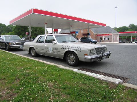 1991 Ford Crown Victoria - A Rhode Island State Police car is parked at a gas station, with another car visible behind it.