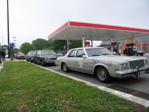 1991 Ford Crown Victoria - Police vehicles queue at a gas station under a red and white canopy.