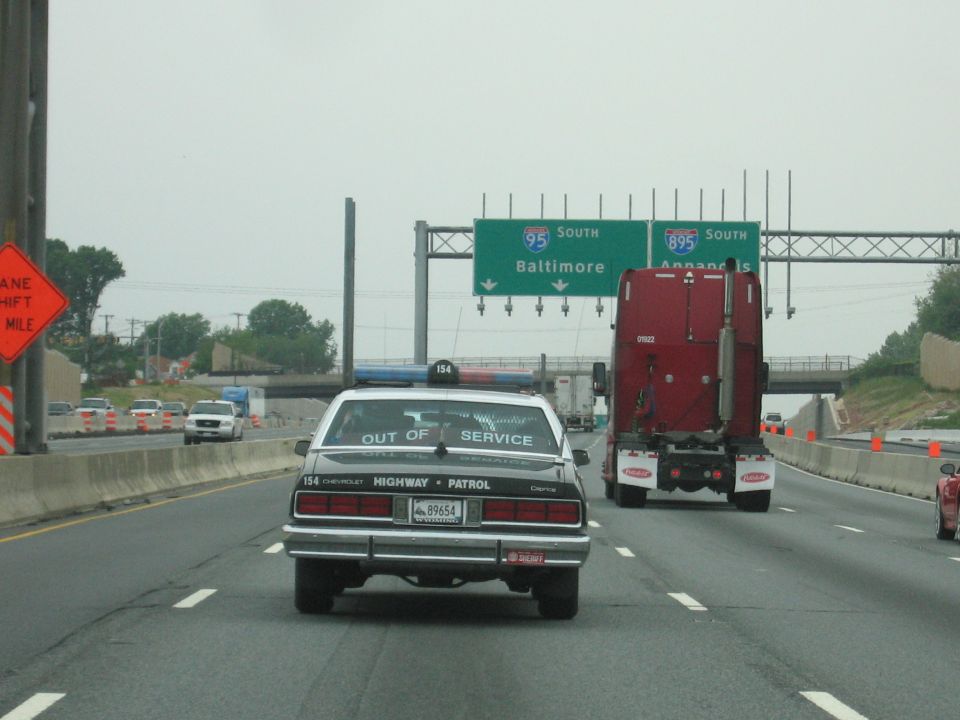 Black police car following red semi truck on I-95 toward Baltimore