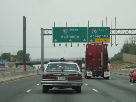 1991 Ford Crown Victoria - A Chevrolet Highway Patrol car is seen on the highway, displaying 'OUT OF SERVICE' on its rear window.
