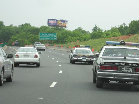1991 Ford Crown Victoria - A Chevrolet Highway Patrol car is seen on the highway, marked as "OUT OF SERVICE".