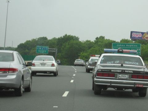 1991 Ford Crown Victoria - Several highway patrol cars are visible on the road, one marked 'OUT OF SERVICE'.