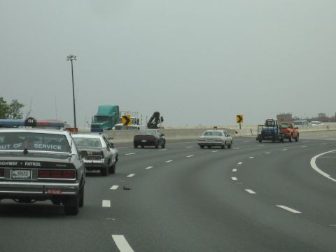 1991 Ford Crown Victoria - A police car marked "OUT OF SERVICE" is seen on the highway alongside other vehicles.