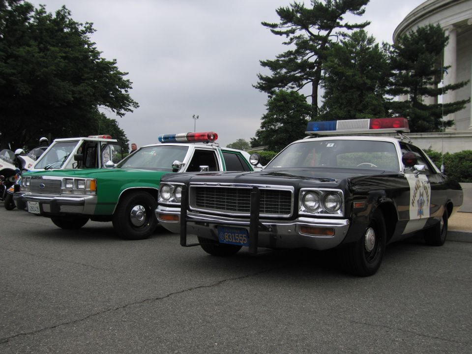 Black California Highway Patrol Dodge sedan and green sheriff car parked