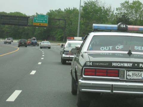 1991 Ford Crown Victoria - A Chevrolet police car with 'OUT OF SERVICE' text is seen on the highway.