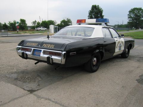 1991 Ford Crown Victoria - This vintage highway patrol car is parked on an asphalt surface under an overcast sky.