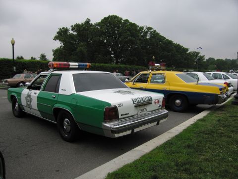 1991 Ford Crown Victoria - Two police cars, a 1991 Ford Crown Victoria and an older model, are parked side-by-side.