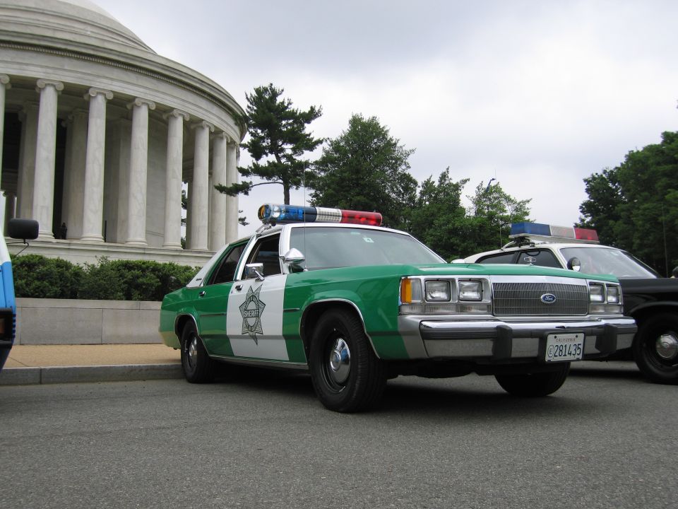 Green and white Ford Sheriff sedan parked in front of the domed Jefferson Memorial