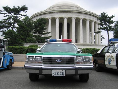 1991 Ford Crown Victoria - 1991 Ford Crown Victoria police car in front of a large domed building, with another patrol car to the right.