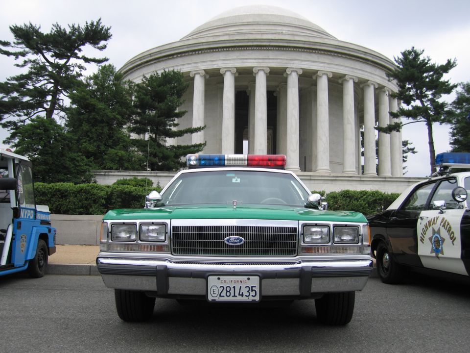 Front view of a green and white Ford Sheriff sedan before the domed Jefferson Memorial