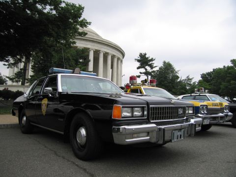 1991 Ford Crown Victoria - Several police cars are parked in front of a large domed building.