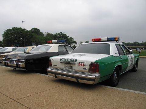 1991 Ford Crown Victoria - Two police cars, a 1991 Ford Crown Victoria Sheriff's vehicle and a National Patrol car, are parked side-by-side.