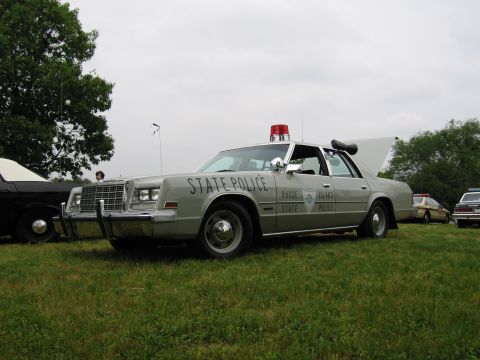 1991 Ford Crown Victoria - A gray police car with "STATE POLICE" text and "RHODE ISLAND STATE POLICE" emblem is parked on a grassy field.