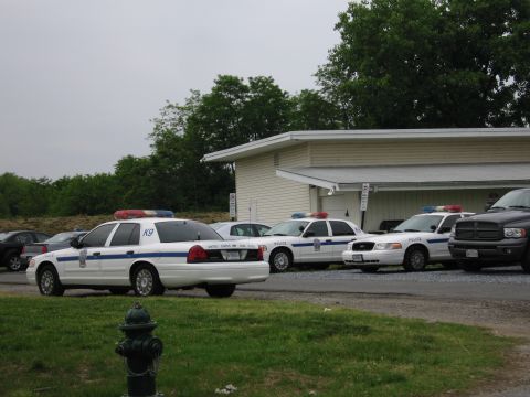 1991 Ford Crown Victoria - Multiple police vehicles, including a K9 unit, are parked outside a building.